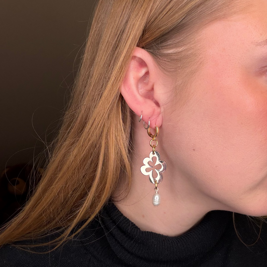 Creolerna är i rostfritt stål med stift i kirurgisk stål, täckta med 18 karats guld tillsammans med de små guldringarna. Blomman är i rostfritt stål och täckt med sterling silver som tål slitage och behåller sin lyster. Ett statement-smycke som utstrålar både elegans och lyx.