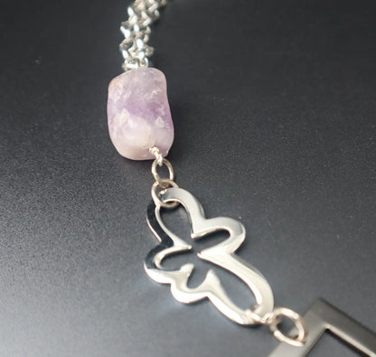 Ametist Perfection Halsband av Design by Brandeby har en dekorativ blomberlock och en rå ametiststen på en silverkedja. Den ljuslila pärlan kontrasterar vackert mot den eleganta svarta bakgrunden och framhäver dess elegans i sterling silver.
