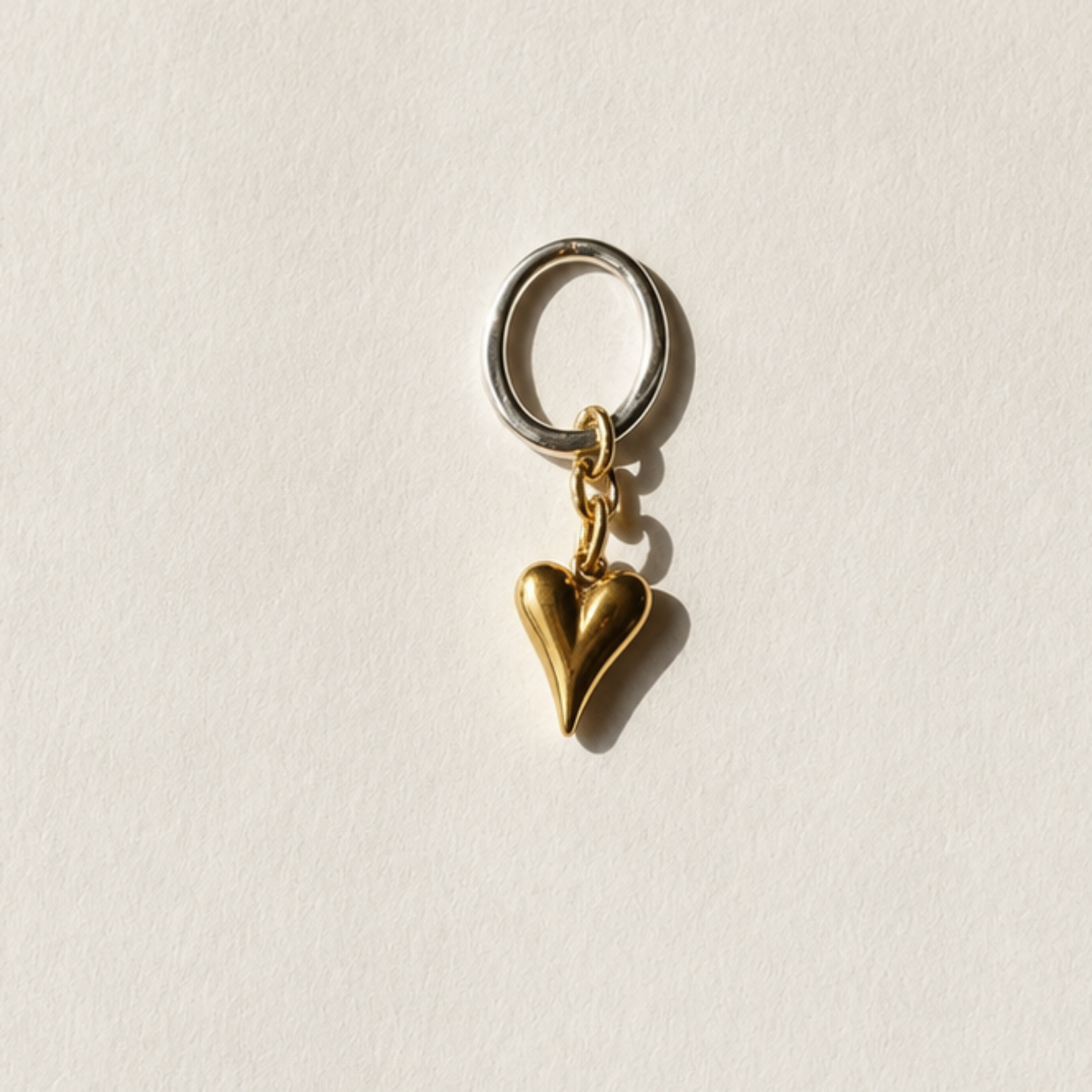 Elegant hjärthänge med massivt guldhjärta i rostfritt stål med 18K guld PVD-beläggning och egendesignad silvercirkel med sterling silver-pläterade detaljer. Ett tidlöst smycke från Design by Brandeby.