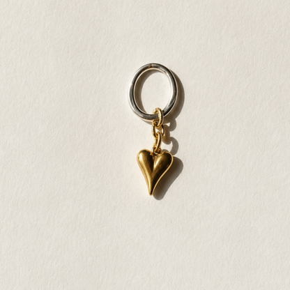 Elegant hjärthänge med massivt guldhjärta i rostfritt stål med 18K guld PVD-beläggning och egendesignad silvercirkel med sterling silver-pläterade detaljer. Ett tidlöst smycke från Design by Brandeby.