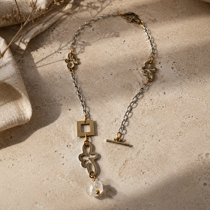 Kort halsband med äkta rå bergkristall, egendesignade blommor i rostfritt stål med sterling silver-pläterade detaljer och gulddetaljer med 18K guld PVD-beläggning. Texturerad kedja och handgjord design från Design by Brandeby.