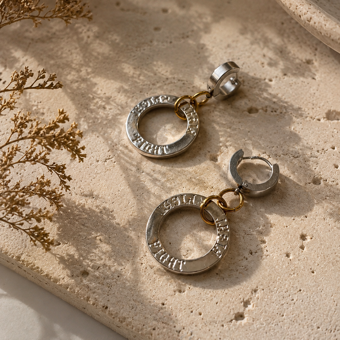 Fight Circle Örhängen med kirurgiska stift, silverfärgade ringar och detaljer i 18K guld PVD. Handgjorda örhängen med budskapet "Fight" från Design by Brandeby.