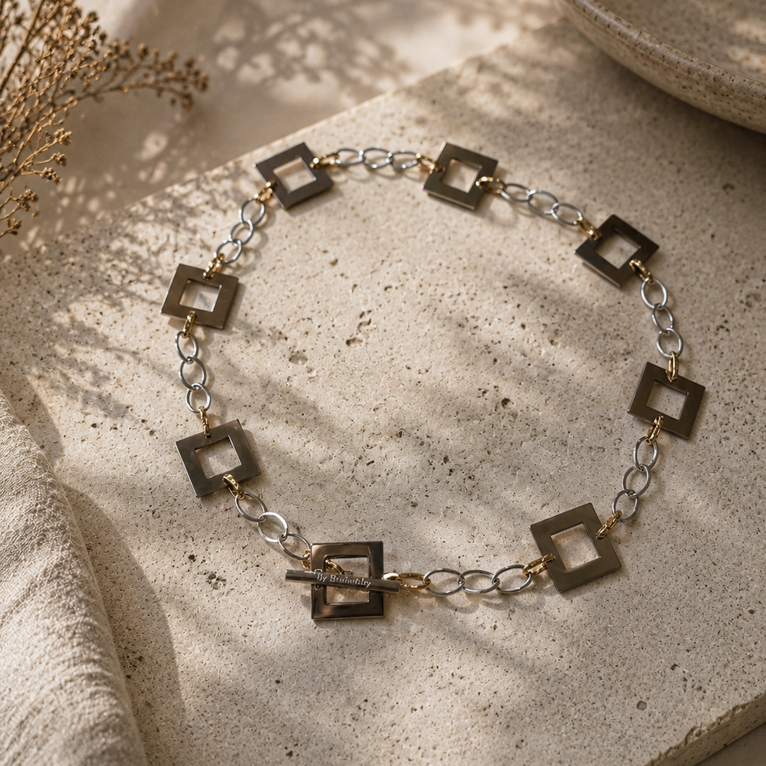 Silver Square Halsband med egendesignade fyrkanter i rostfritt stål med sterling silver-pläterade detaljer. PVD-behandlad silverkedja och gulddetaljer. Längd 53 cm.