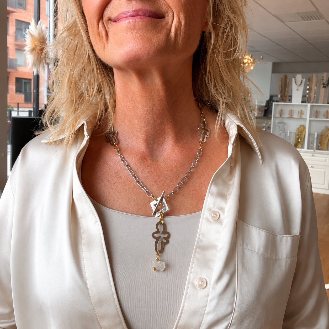 Kort halsband med äkta rå bergkristall, egendesignade blommor i rostfritt stål med sterling silver-pläterade detaljer och gulddetaljer med 18K guld PVD-beläggning. Texturerad kedja och handgjord design från Design by Brandeby.