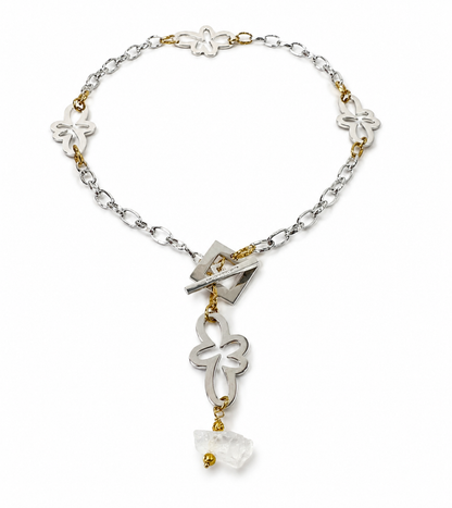Halsband med äkta rå bergkristall, silverfärgad kedja, egendesignade blommor och guldringar i 18K PVD. Handgjort i rostfritt stål med sterling silver-pläterade detaljer. Ett unikt statementhalsband från Design by Brandeby.