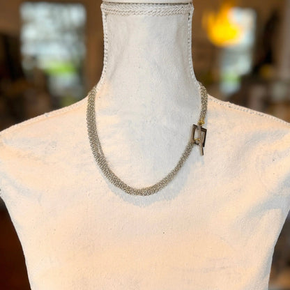 The Circle Of Life Halsband av Design by Brandeby, ett halsband med kedja i sterling silver med ett elegant spänne, visas på en vit skyltdockabyst mot en suddig bakgrund.