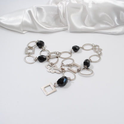 svart fasettslipad onyx stenar i ett långt halsbande med silverdelar design by brandeby