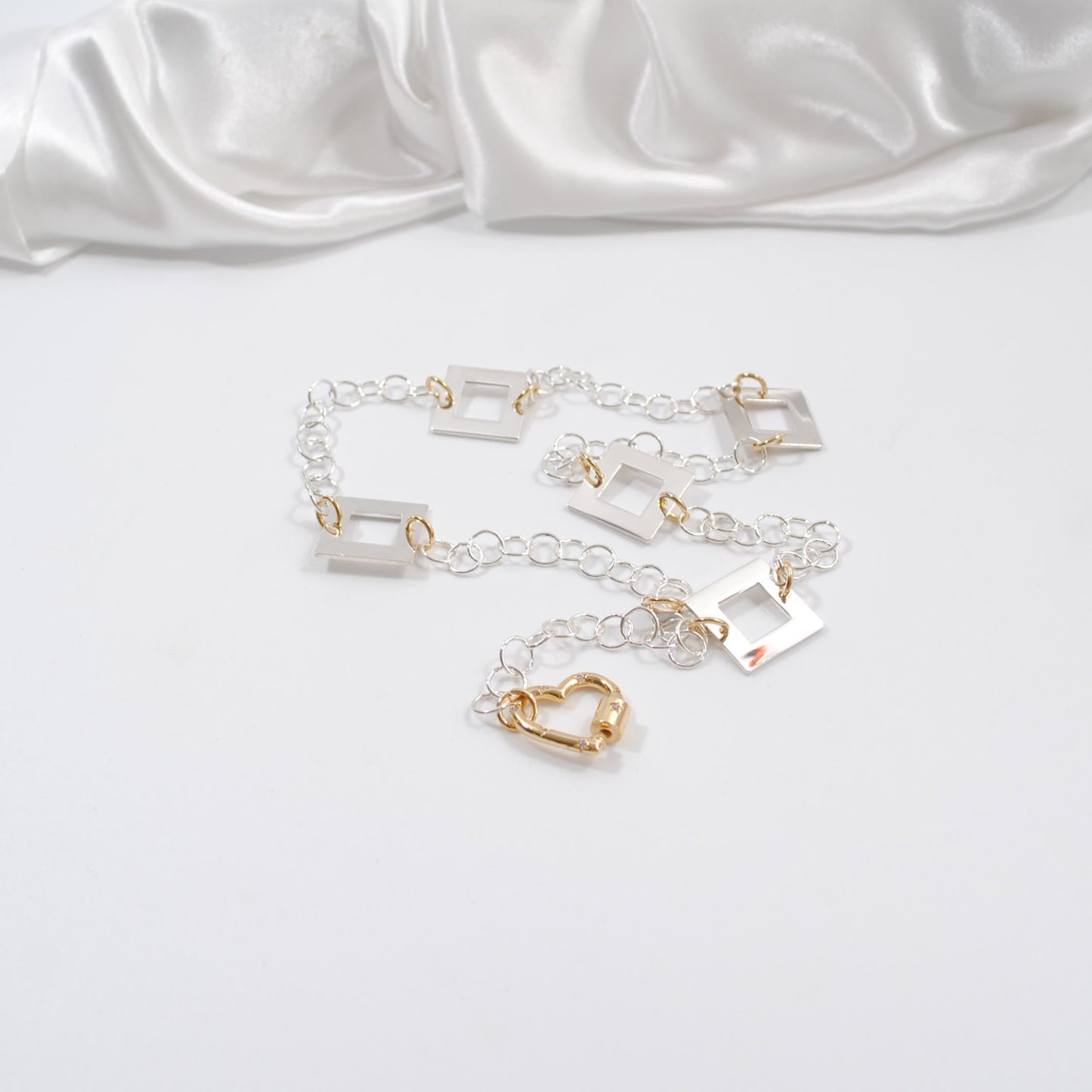 kort silver halsband med fyrkanter guld detaljer och handgjord kedja med ett guld hjärta som lås design by brandeby