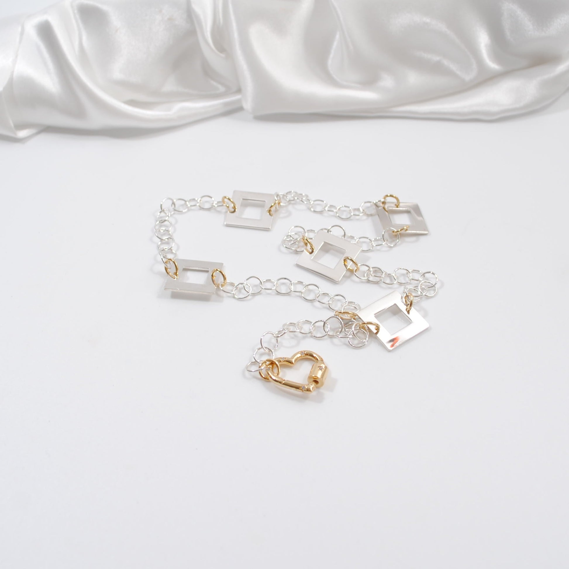 kort silver halsband med fyrkanter guld detaljer och handgjord kedja med ett guld hjärta som lås design by brandeby