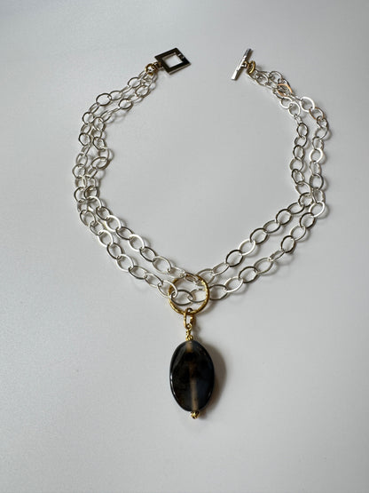 Elegant hänge med äkta svart agat och tunn guldring i rostfritt stål med 18K PVD-plätering. Ett stilrent och tidlöst smycke som passar både vardag och fest. Handgjort av Design by Brandeby.