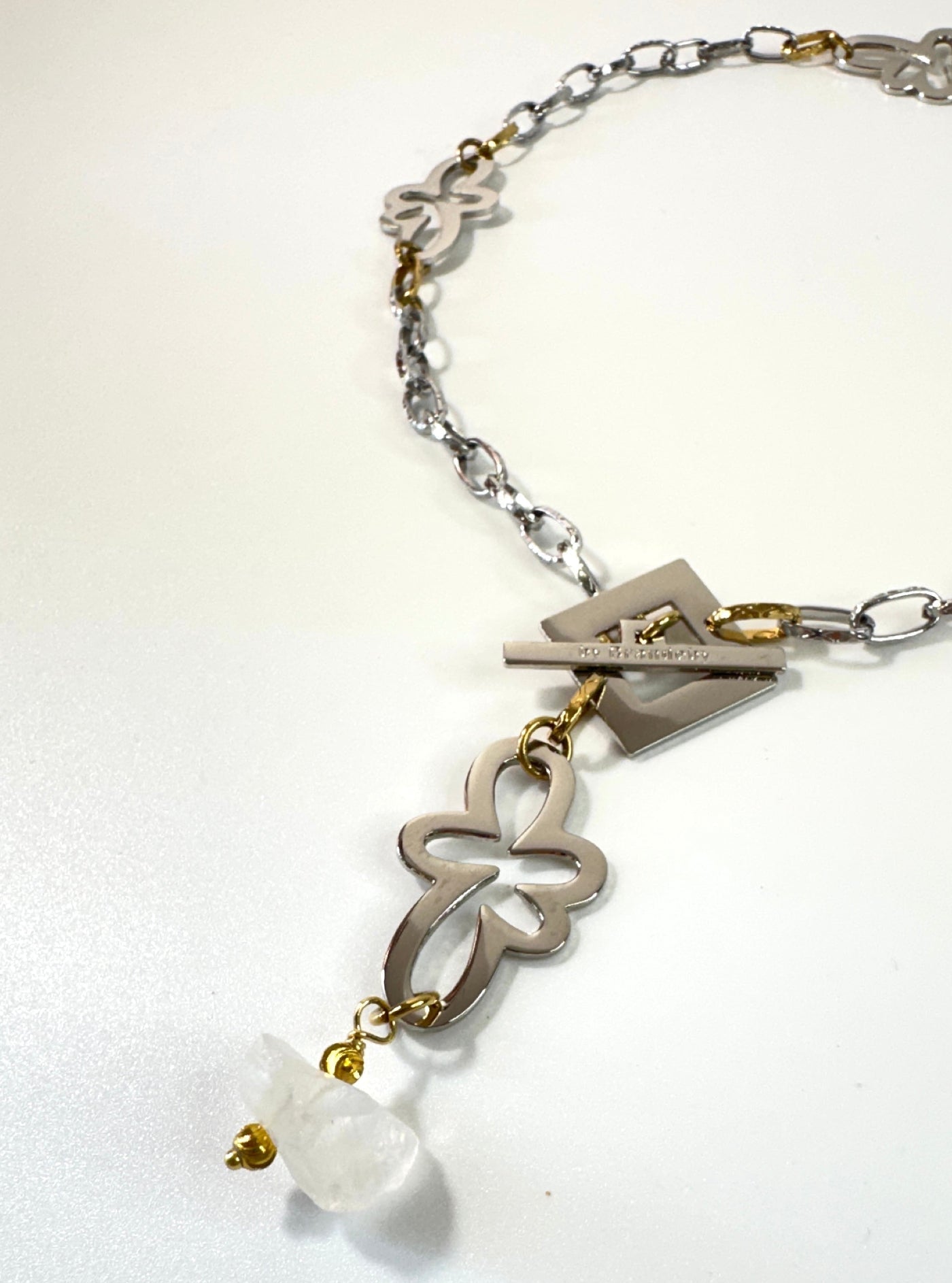 Kort halsband med äkta rå bergkristall, egendesignade blommor i rostfritt stål med sterling silver-pläterade detaljer och gulddetaljer med 18K guld PVD-beläggning. Texturerad kedja och handgjord design från Design by Brandeby.