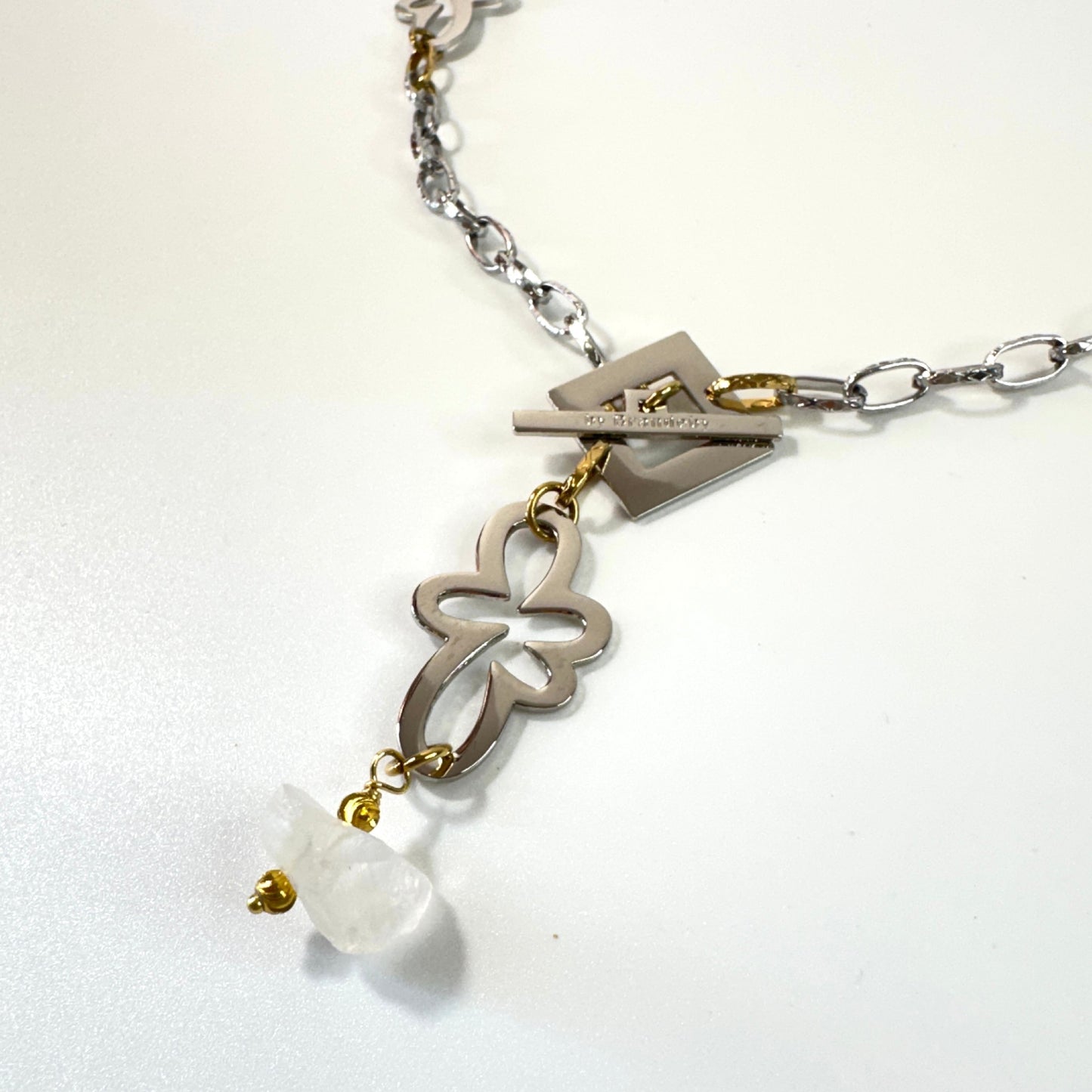 Halsband med äkta rå bergkristall, silverfärgad kedja, egendesignade blommor och guldringar i 18K PVD. Handgjort i rostfritt stål med sterling silver-pläterade detaljer. Ett unikt statementhalsband från Design by Brandeby.