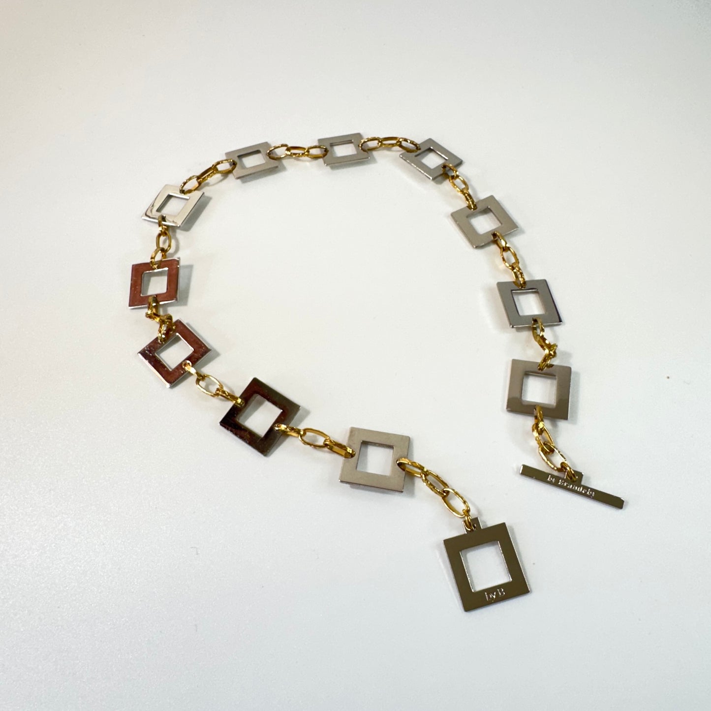 Infinity Square Halsband från Design by Brandeby med egendesignade fyrkanter i rostfritt stål med sterling silver-pläterade detaljer och texturerade guldringar i 18K PVD.