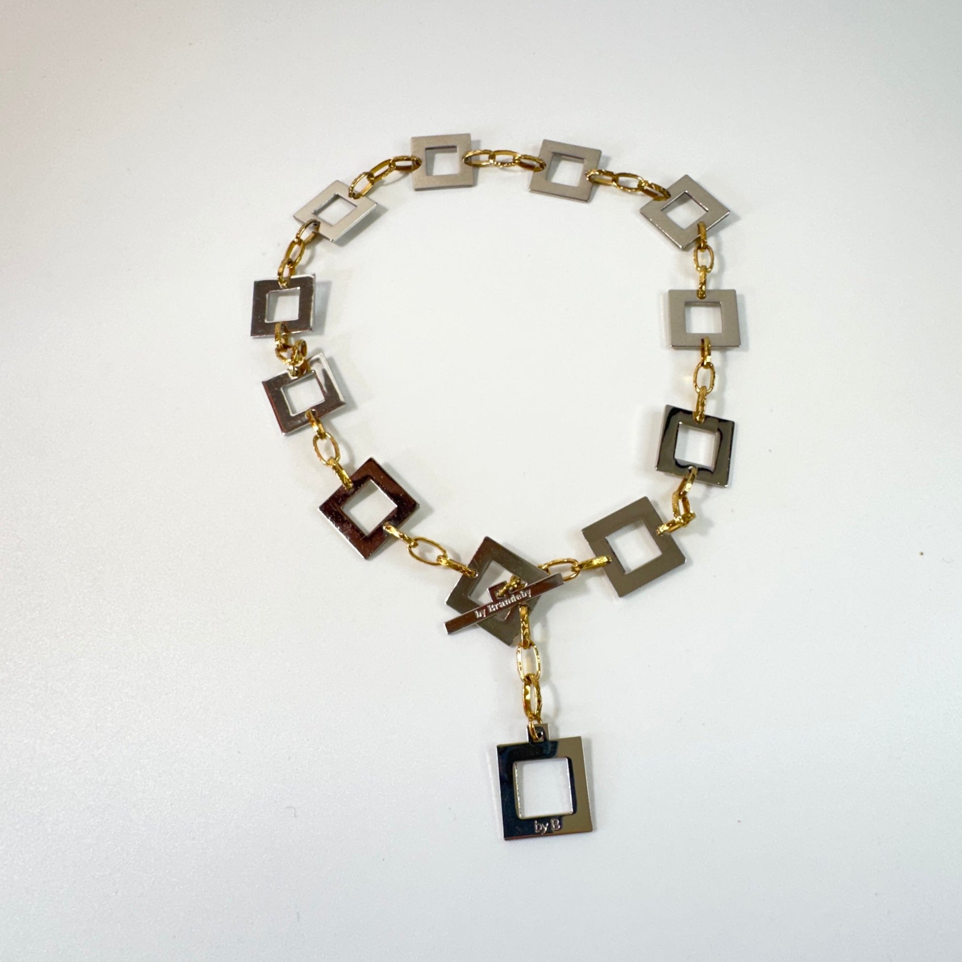 Infinity Square Halsband från Design by Brandeby med egendesignade fyrkanter i rostfritt stål med sterling silver-pläterade detaljer och texturerade guldringar i 18K PVD.