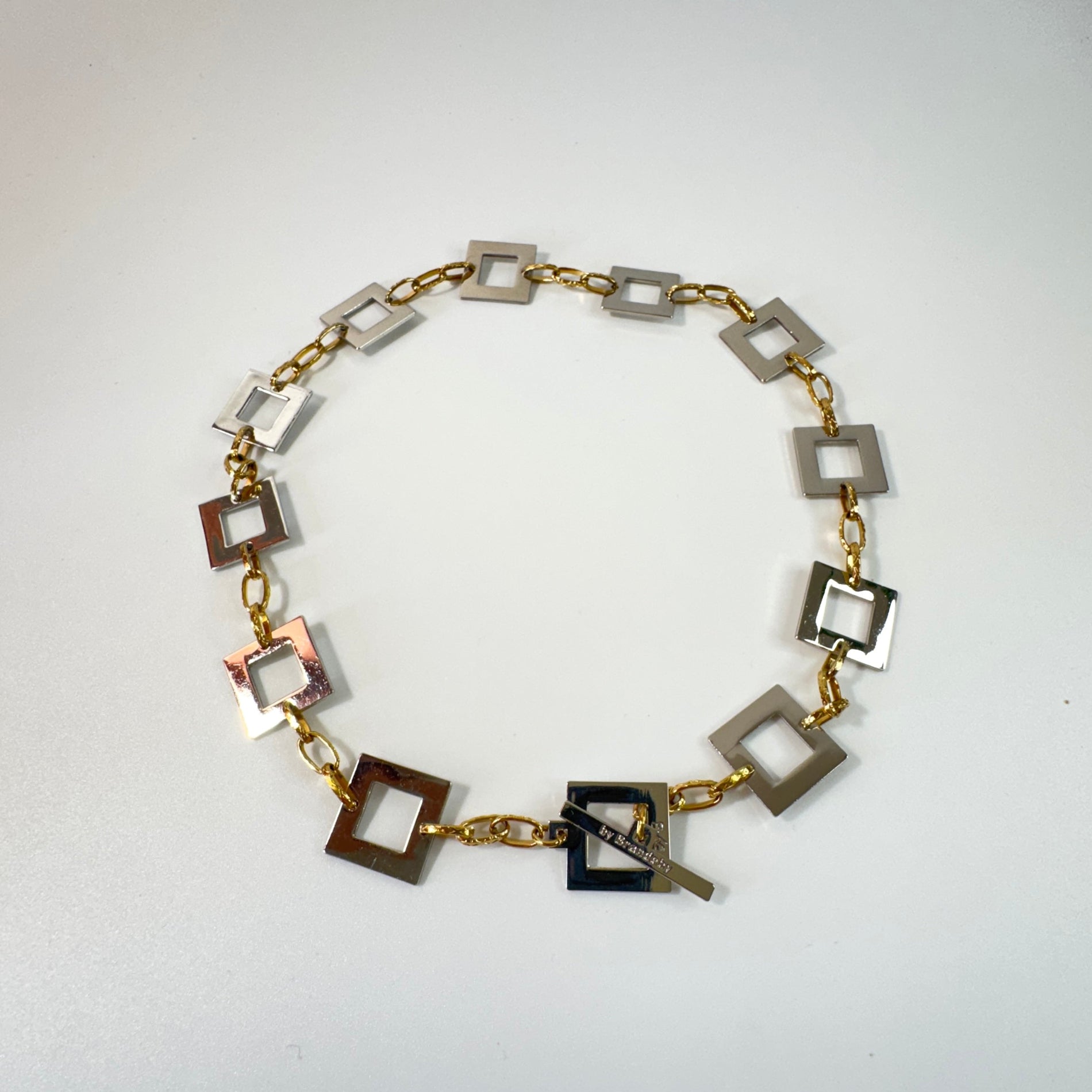 Infinity Square Halsband från Design by Brandeby med egendesignade fyrkanter i rostfritt stål med sterling silver-pläterade detaljer och texturerade guldringar i 18K PVD.