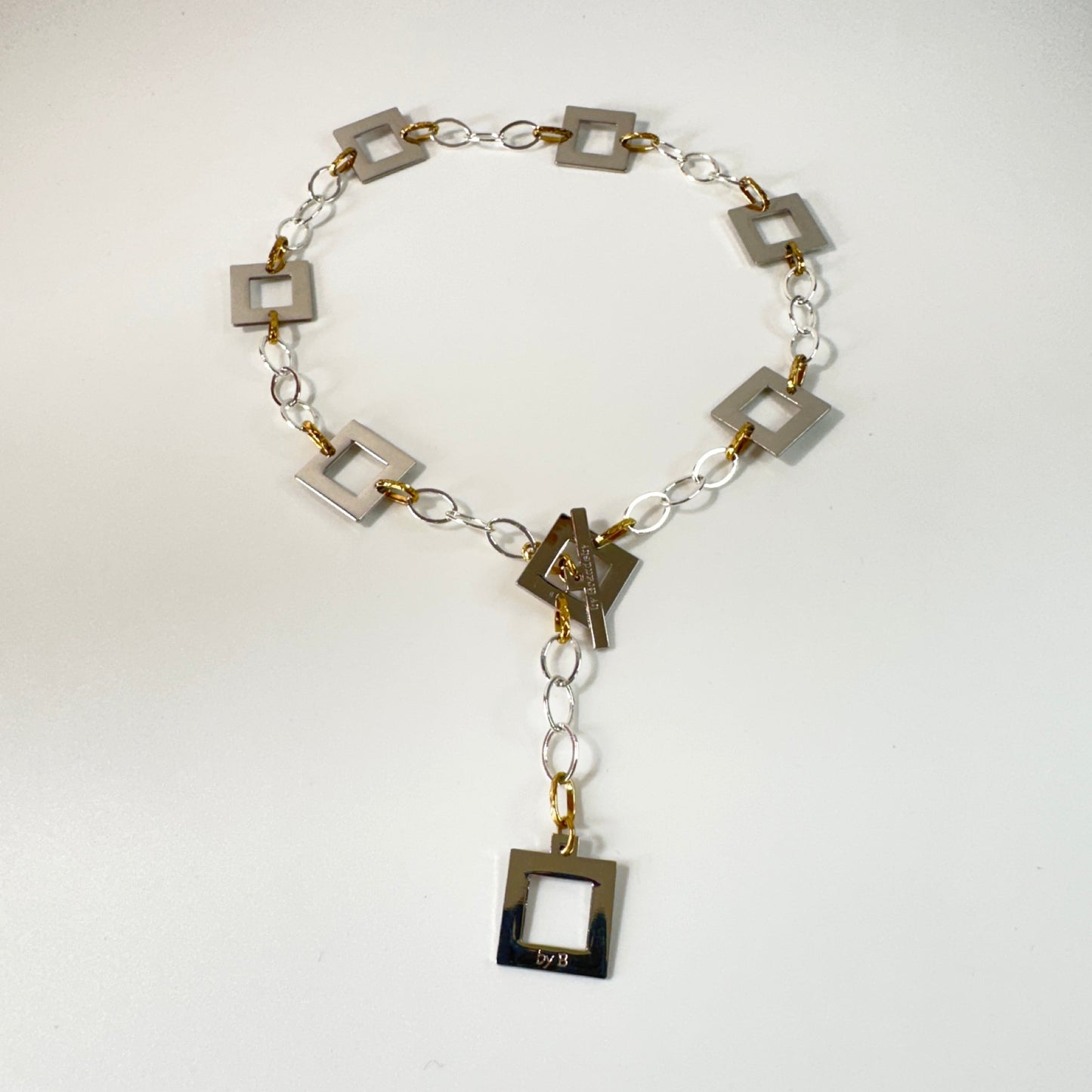 Silver Square Halsband med egendesignade fyrkanter i rostfritt stål med sterling silver-pläterade detaljer. PVD-behandlad silverkedja och gulddetaljer. Längd 53 cm.