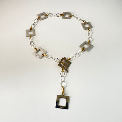 Silver Square Halsband med egendesignade fyrkanter i rostfritt stål med sterling silver-pläterade detaljer. PVD-behandlad silverkedja och gulddetaljer. Längd 53 cm.