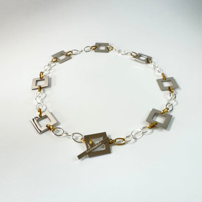 Silver Square Halsband med egendesignade fyrkanter i rostfritt stål med sterling silver-pläterade detaljer. PVD-behandlad silverkedja och gulddetaljer. Längd 53 cm.