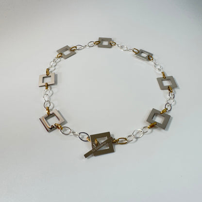Silver Square Halsband med egendesignade fyrkanter i rostfritt stål med sterling silver-pläterade detaljer. PVD-behandlad silverkedja och gulddetaljer. Längd 53 cm.