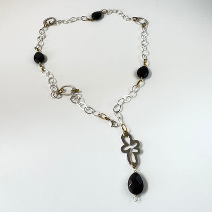 Långt halsband med fasettslipad svart onyx, paperclip-kedja och egendesignade detaljer i rostfritt stål med sterling silver-pläterade detaljer. Guldringar med 18K guld PVD-beläggning och flexibel längd. Design by Brandeby.