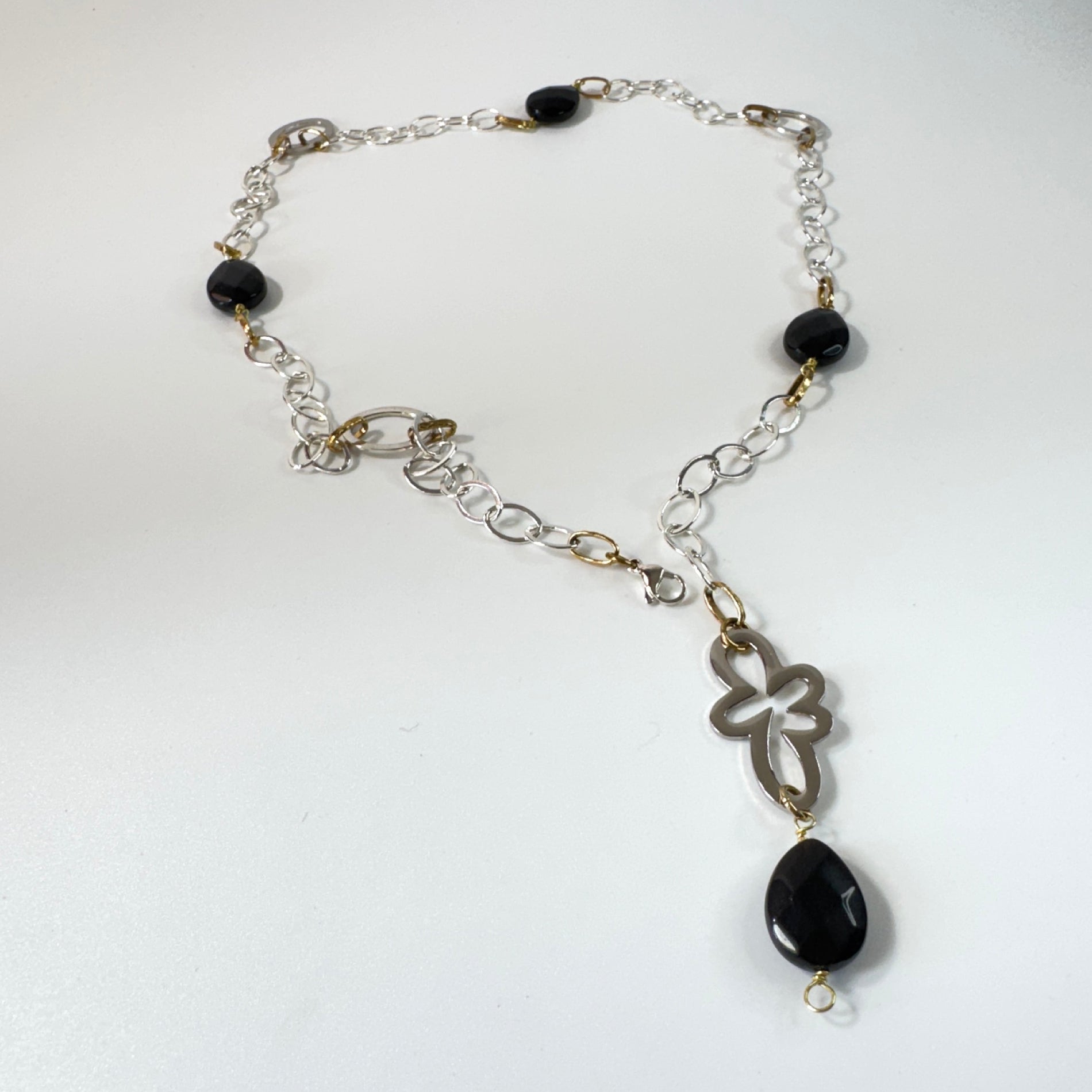Långt halsband med fasettslipad svart onyx, paperclip-kedja och egendesignade detaljer i rostfritt stål med sterling silver-pläterade detaljer. Guldringar med 18K guld PVD-beläggning och flexibel längd. Design by Brandeby.