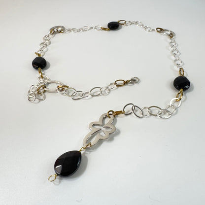 Långt halsband med fasettslipad svart onyx, paperclip-kedja och egendesignade detaljer i rostfritt stål med sterling silver-pläterade detaljer. Guldringar med 18K guld PVD-beläggning och flexibel längd. Design by Brandeby.
