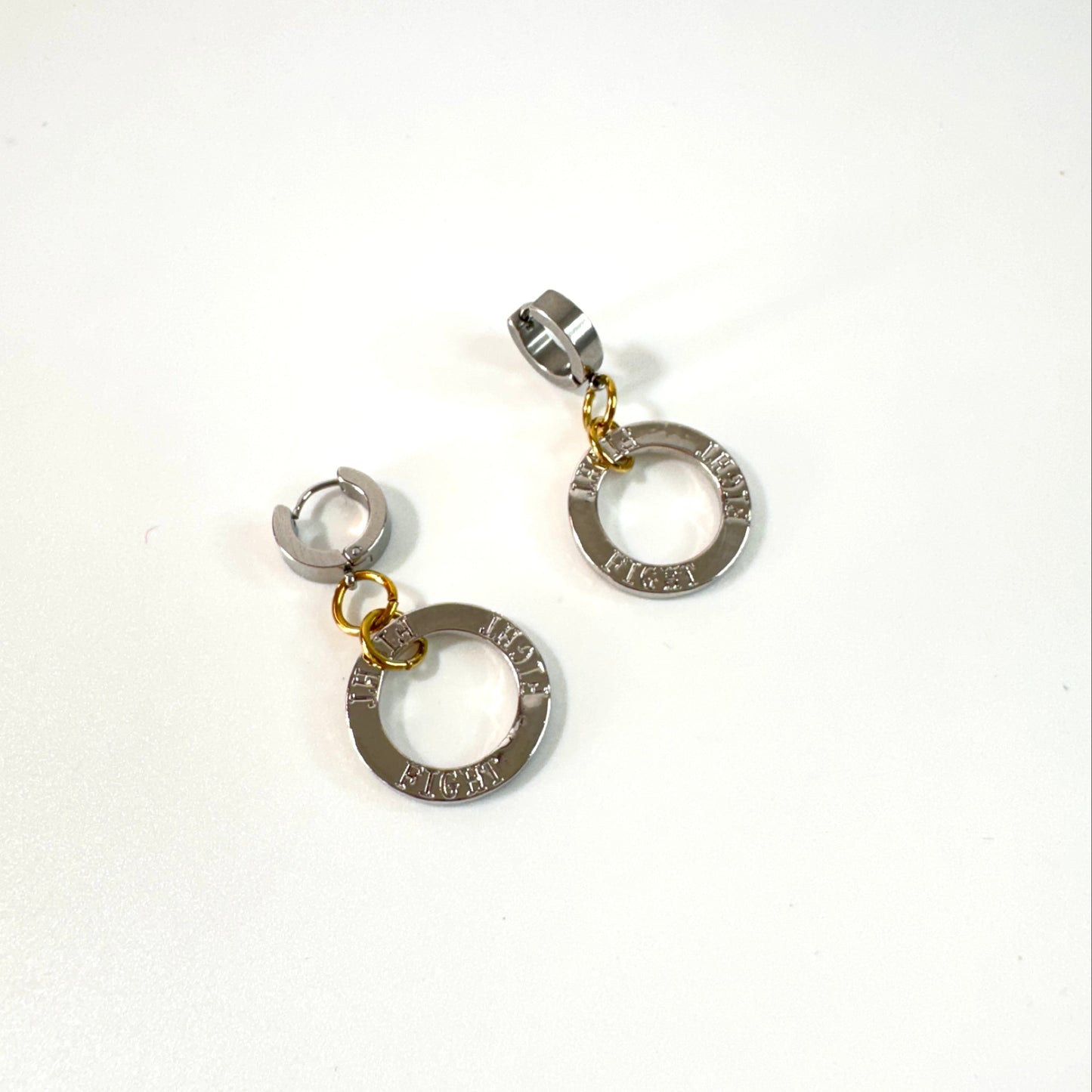 Fight Circle Örhängen med kirurgiska stift, silverfärgade ringar och detaljer i 18K guld PVD. Handgjorda örhängen med budskapet "Fight" från Design by Brandeby.