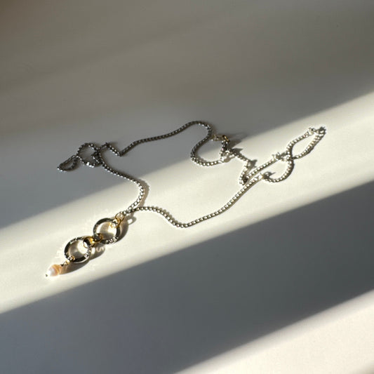 Flexibelt halsband med två cirklar med texten Fight, äkta vit sötvattenspärla och gulddetaljer i 18K PVD. Bär det kort eller långt för olika uttryck. Handgjort av Design by Brandeby.