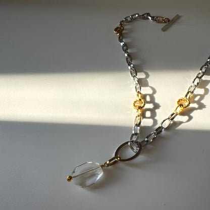 Elegant hänge med äkta bergkristall, fasade kanter och egendesignad cirkel i rostfritt stål med sterling silver-pläterade detaljer. Gulddetaljer i rostfritt stål med 18K guld PVD-beläggning. Handgjort av Design by Brandeby.