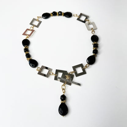 Kort halsband med fasettslipad svart onyx, egendesignade silverdetaljer och 18K guld PVD. Kan knäppas på två ställen. Handgjort av Sussie Brandeby i Helsingborg.