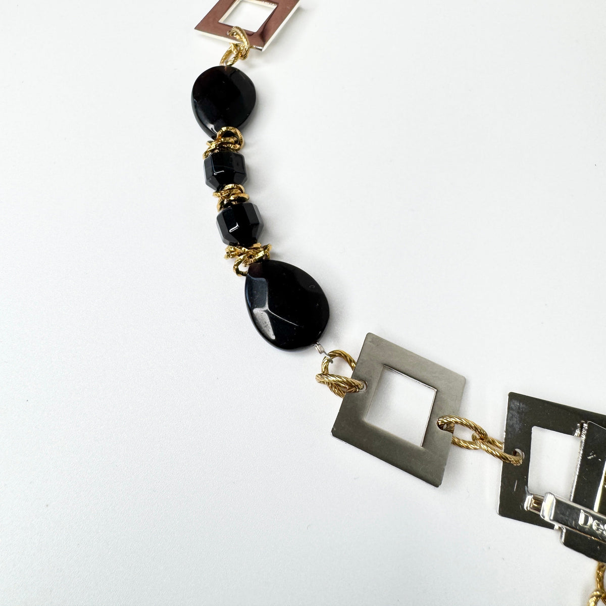 Kort halsband med fasettslipad svart onyx, egendesignade silverdetaljer och 18K guld PVD. Kan knäppas på två ställen. Handgjort av Sussie Brandeby i Helsingborg.
