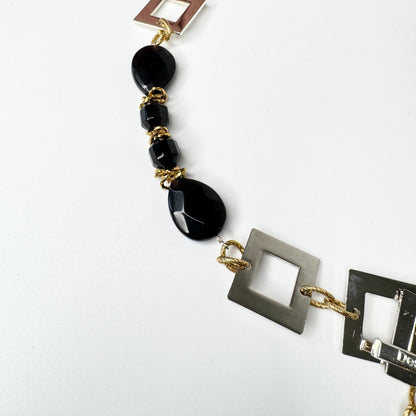 Kort halsband med fasettslipad svart onyx, egendesignade silverdetaljer och 18K guld PVD. Kan knäppas på två ställen. Handgjort av Sussie Brandeby i Helsingborg.
