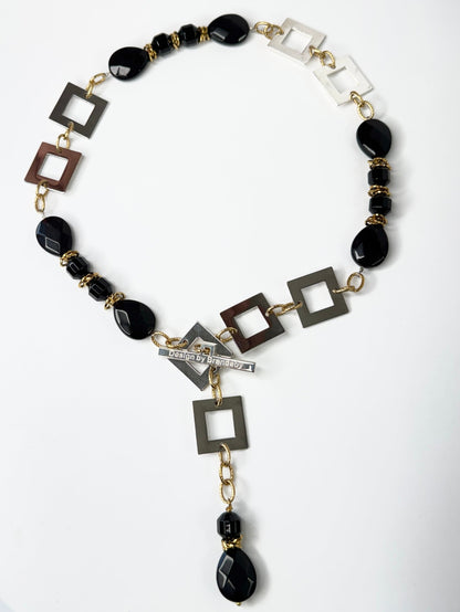 Kort halsband med fasettslipad svart onyx, egendesignade silverdetaljer och 18K guld PVD. Kan knäppas på två ställen. Handgjort av Sussie Brandeby i Helsingborg.