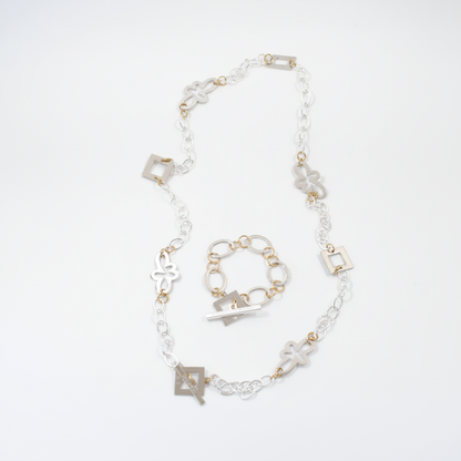Långt handgjort halsband med egendesignade fyrkanter och blommor, silverpläterad mässingskedja och detaljer i 18K guld PVD. Bär på flera sätt. Design by Brandeby