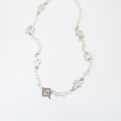 Långt handgjort halsband med egendesignade fyrkanter och blommor, silverpläterad mässingskedja och detaljer i 18K guld PVD. Bär på flera sätt. Design by Brandeby